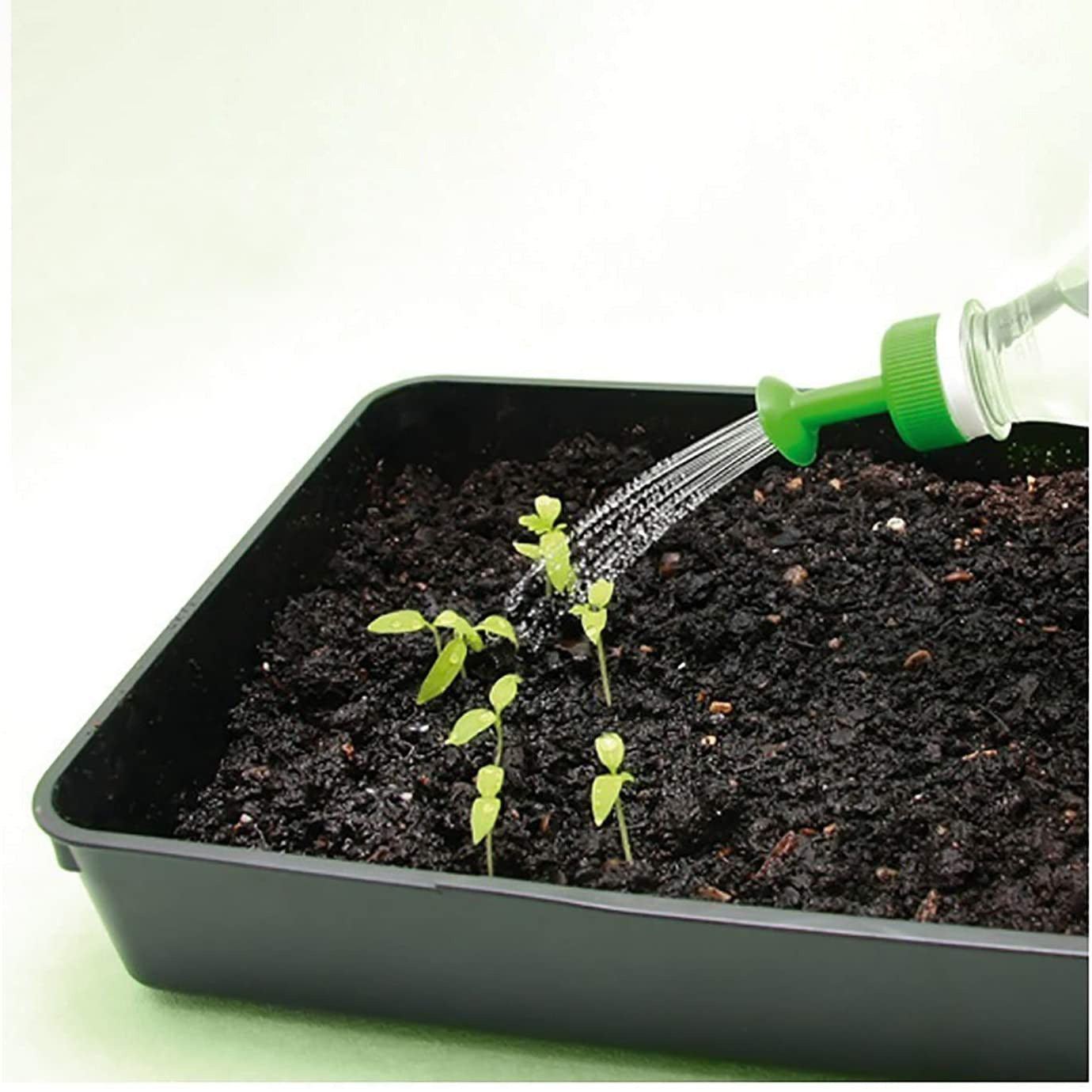 Beverage Bottle Watering Nozzle - image of the product being used to water plants in a pot