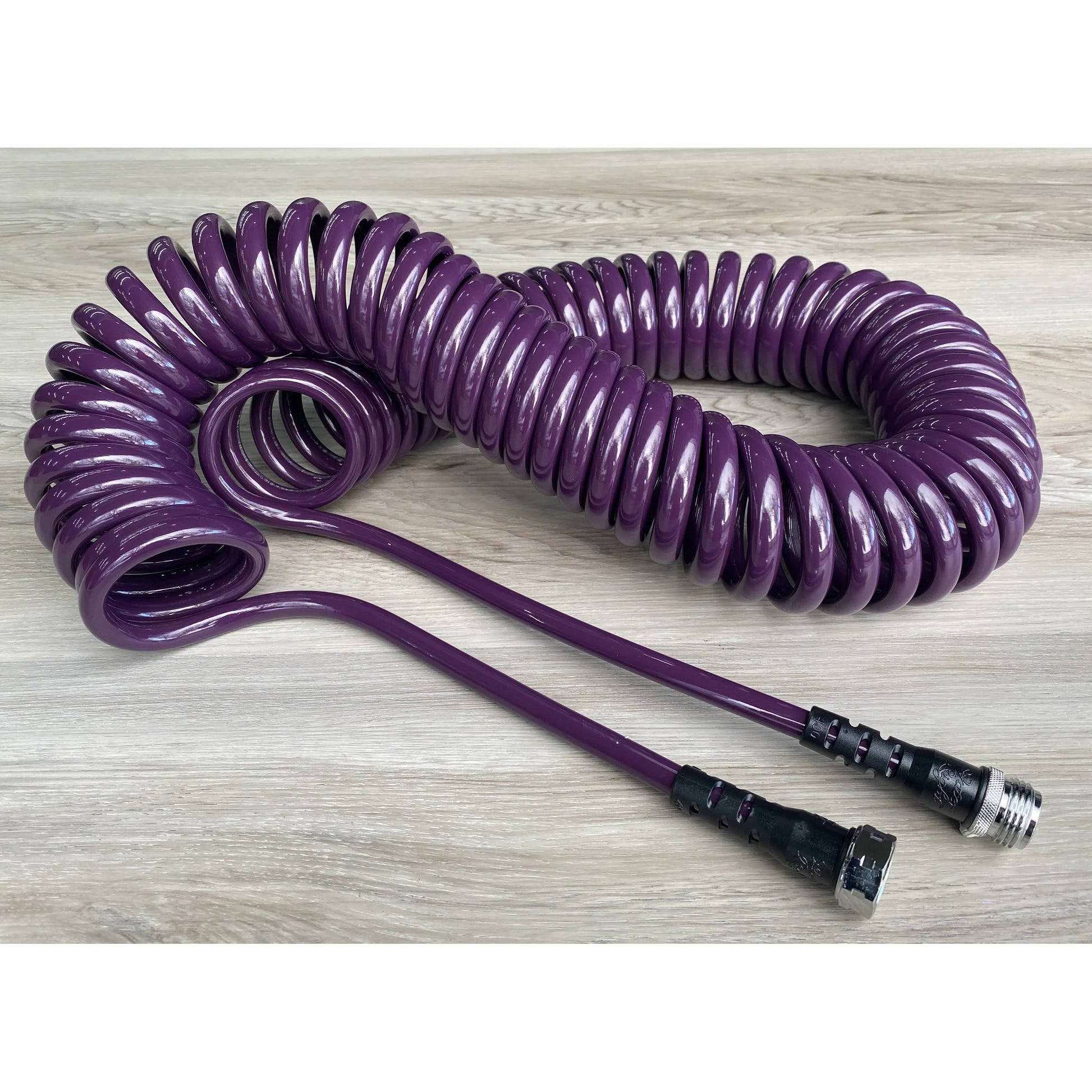Coiled Garden Hose – 3/8” ID: Image of the purple coiled garden hose on a wooden table