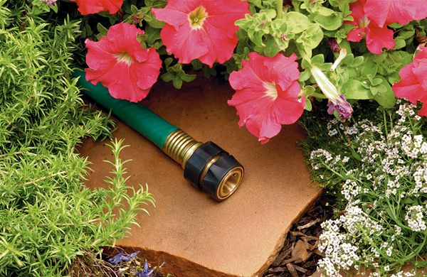 Brass Quick Connect Hose Fitting Set - image of the product on a garden hose surrounded by plants