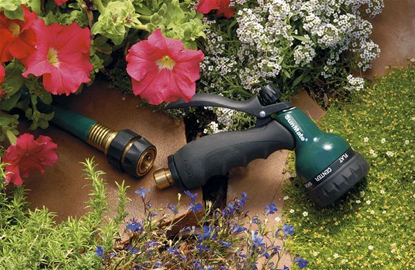 Brass Quick Connect Hose Fitting Set - image of the product on a garden hose surrounded by plants and facuet