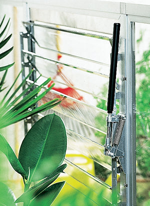 Liberty Automatic Louver Opener - on the greenhouse wall surrounded by plants