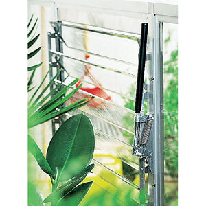 Liberty Automatic Louver Opener - on the greenhouse wall surrounded by plants
