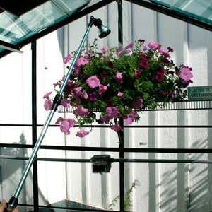 Telescoping Water Wand being used to water a hanging plant in a greenhouse