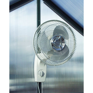Wall Mount Oscillating Fan, 12" - image of the product mounted on the wall of a greenhouse