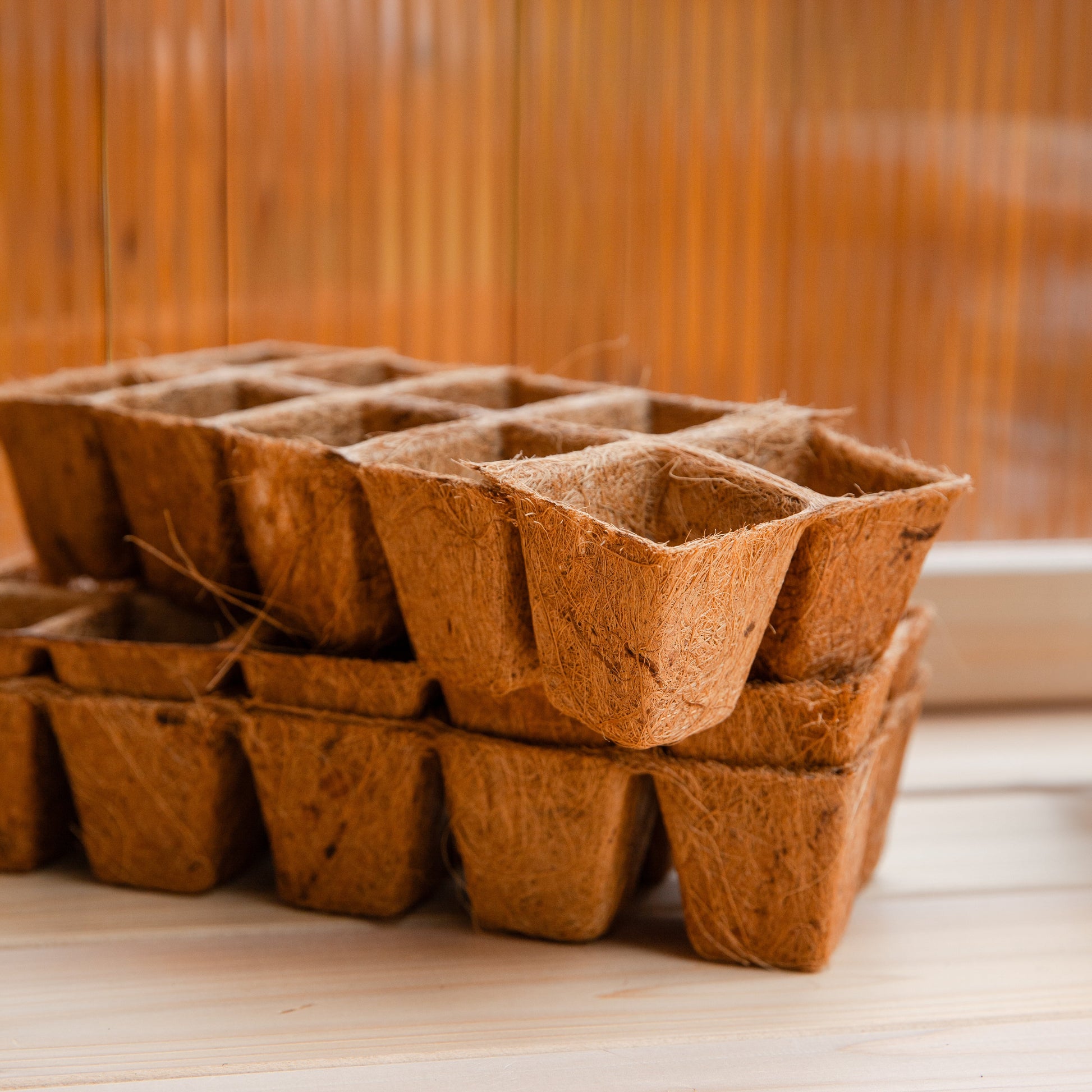Stack of biodegradable PlantBest Coir Pot Refills on a cedar potting bench  